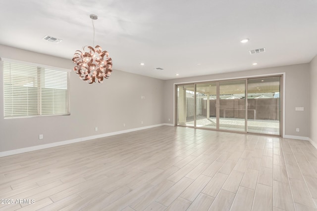 unfurnished room with light wood-type flooring, a wealth of natural light, and a chandelier