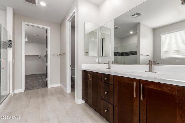 bathroom with vanity, toilet, and a shower with door