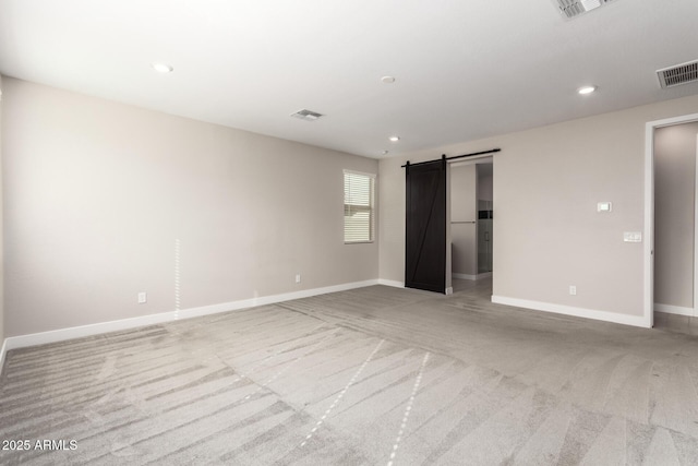 unfurnished bedroom featuring a barn door and light colored carpet