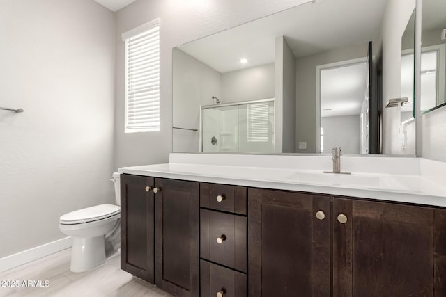 bathroom featuring a shower with door, vanity, and toilet