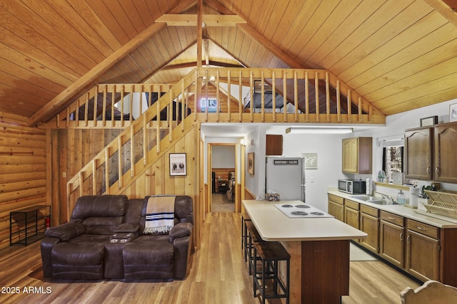 kitchen featuring rustic walls, sink, light hardwood / wood-style flooring, a kitchen breakfast bar, and stainless steel appliances