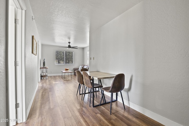 dining space featuring hardwood / wood-style flooring, a textured ceiling, and ceiling fan