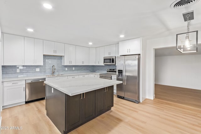 kitchen with sink, a center island, light hardwood / wood-style flooring, white cabinets, and appliances with stainless steel finishes