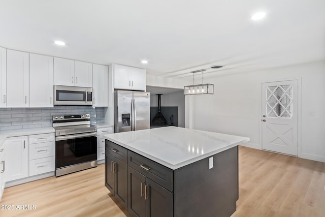 kitchen featuring white cabinetry, a center island, hanging light fixtures, backsplash, and appliances with stainless steel finishes