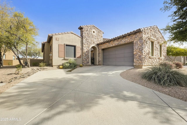 mediterranean / spanish house with stucco siding, a garage, stone siding, driveway, and a tiled roof