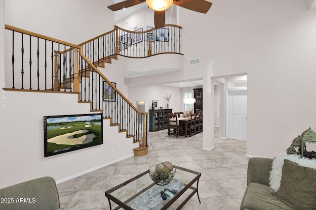 tiled living room featuring ceiling fan and a towering ceiling