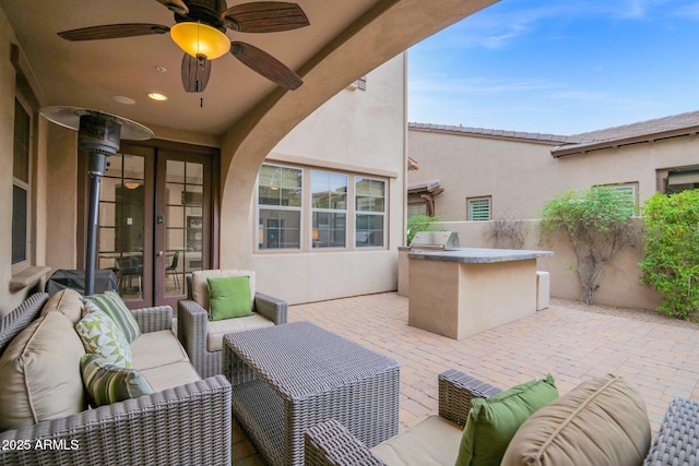 view of patio / terrace with french doors, an outdoor kitchen, outdoor lounge area, ceiling fan, and a grill