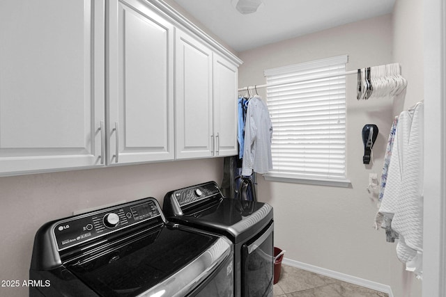 clothes washing area featuring light tile patterned flooring, cabinets, and washing machine and clothes dryer