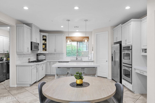 kitchen with appliances with stainless steel finishes, tasteful backsplash, sink, decorative light fixtures, and white cabinetry