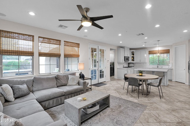 living room with ceiling fan, sink, and french doors