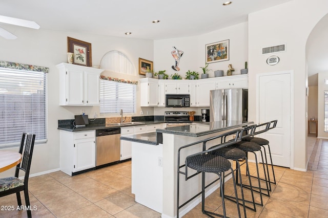 3133 E Redwood Ct, Phoenix, AZ 85048 - kitchen featuring stainless steel appliances, arched walkways, dark countertops, white cabinetry, and light tile patterned floors