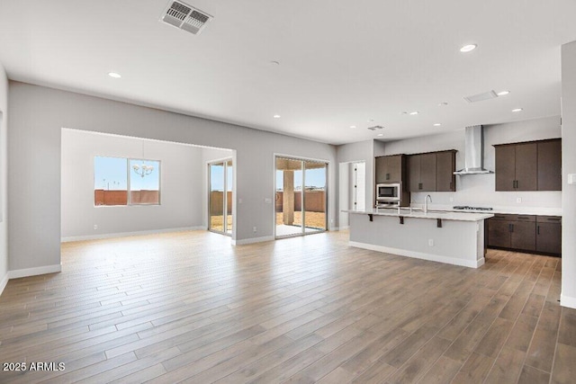 unfurnished living room with recessed lighting, baseboards, visible vents, and light wood finished floors