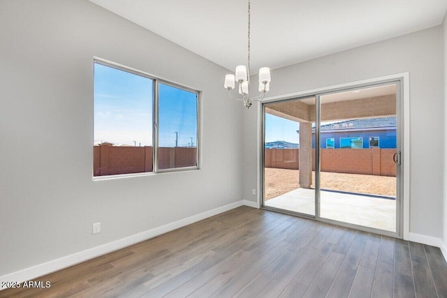 spare room featuring a healthy amount of sunlight, baseboards, and wood finished floors