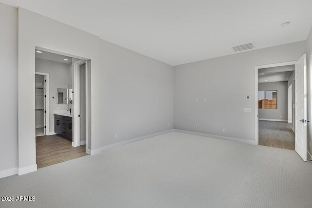 unfurnished bedroom featuring visible vents, baseboards, ensuite bathroom, and carpet