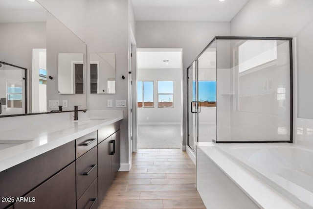 bathroom with double vanity, a bath, a stall shower, and a sink