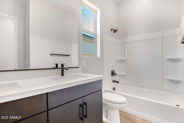 bathroom featuring double vanity, toilet, shower / bathing tub combination, and a sink