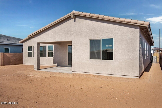 back of house featuring stucco siding, a patio, a fenced backyard, and a tiled roof