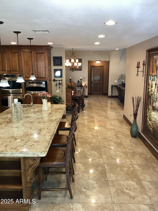 6540 E Wildcat Dr, Cave Creek, AZ 85331 - kitchen featuring double oven, light stone counters, a breakfast bar area, a chandelier, and recessed lighting