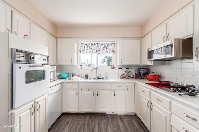 kitchen featuring sink, white appliances, decorative backsplash, and white cabinets