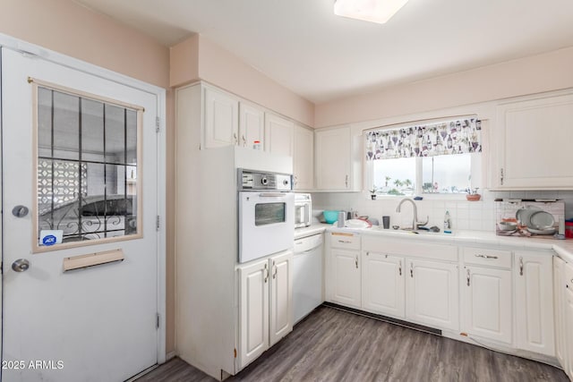 kitchen featuring sink, white appliances, dark wood-type flooring, white cabinetry, and decorative backsplash