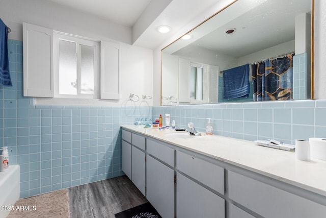 bathroom with vanity, shower / bathtub combination with curtain, wood-type flooring, and tile walls