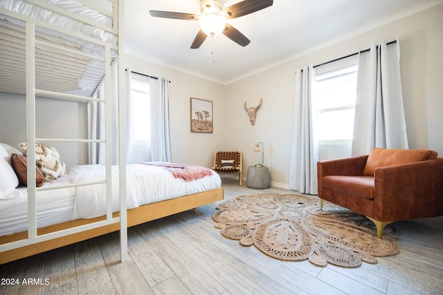 bedroom featuring ceiling fan, hardwood / wood-style flooring, and multiple windows