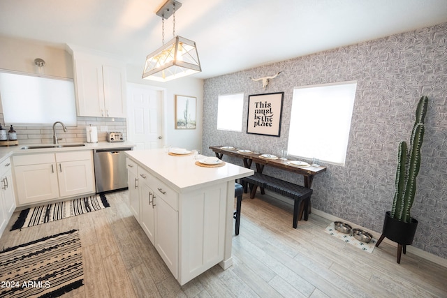 kitchen featuring stainless steel dishwasher, pendant lighting, sink, and white cabinets