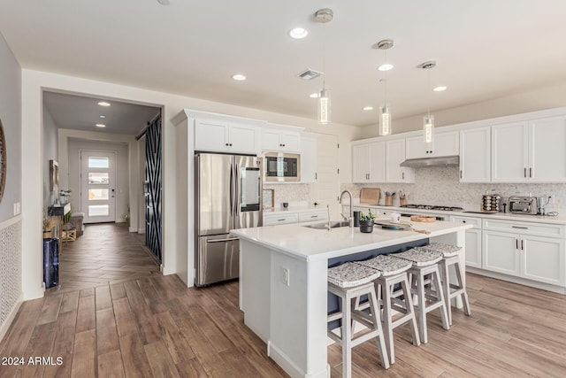 kitchen featuring sink, appliances with stainless steel finishes, decorative light fixtures, light hardwood / wood-style floors, and white cabinetry