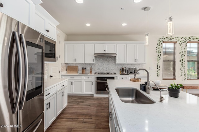 kitchen with pendant lighting, dark wood-type flooring, white cabinets, sink, and stainless steel appliances