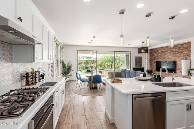 kitchen featuring white cabinetry, sink, pendant lighting, light hardwood / wood-style floors, and appliances with stainless steel finishes