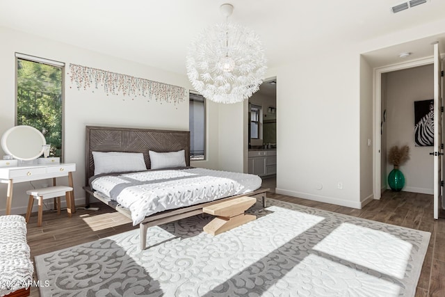 bedroom featuring connected bathroom, an inviting chandelier, and dark wood-type flooring