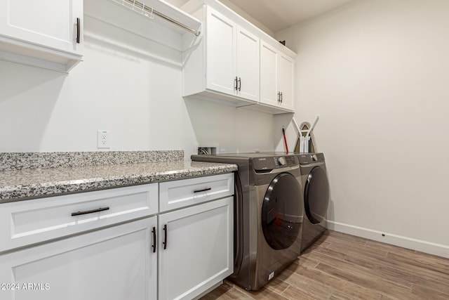 clothes washing area featuring washer and clothes dryer, cabinets, and light hardwood / wood-style flooring