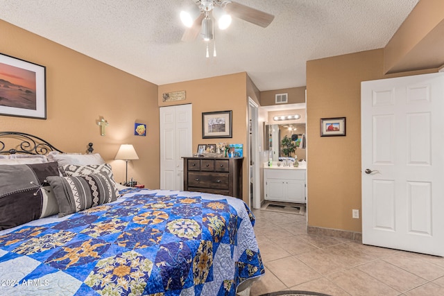 bedroom with ensuite bathroom, a textured ceiling, ceiling fan, and light tile patterned flooring