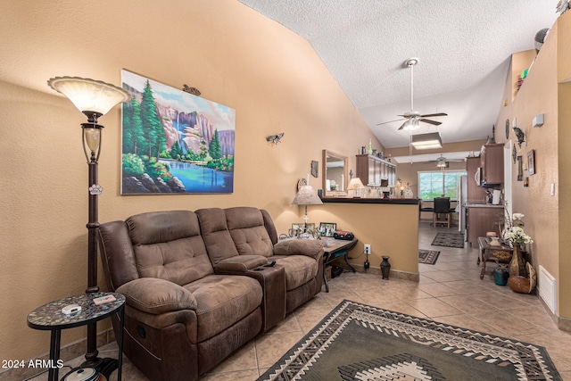 living room with ceiling fan, a textured ceiling, light tile patterned floors, and vaulted ceiling