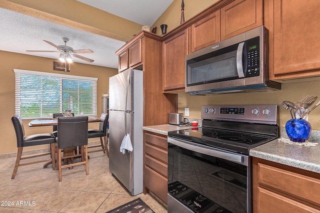 kitchen with a textured ceiling, light tile patterned floors, ceiling fan, and stainless steel appliances