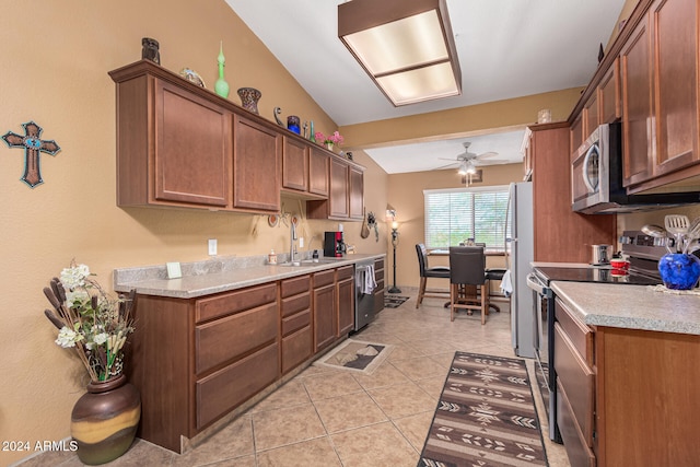 kitchen with stainless steel appliances, sink, ceiling fan, light tile patterned floors, and vaulted ceiling