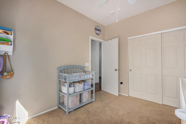 carpeted bedroom with a crib, a closet, and ceiling fan