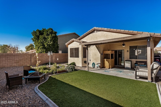 back of property featuring ceiling fan, a patio area, an outdoor fire pit, and a lawn