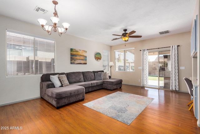 living room with ceiling fan with notable chandelier and hardwood / wood-style floors