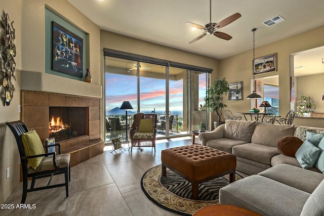 living room featuring ceiling fan, tile patterned floors, and a fireplace