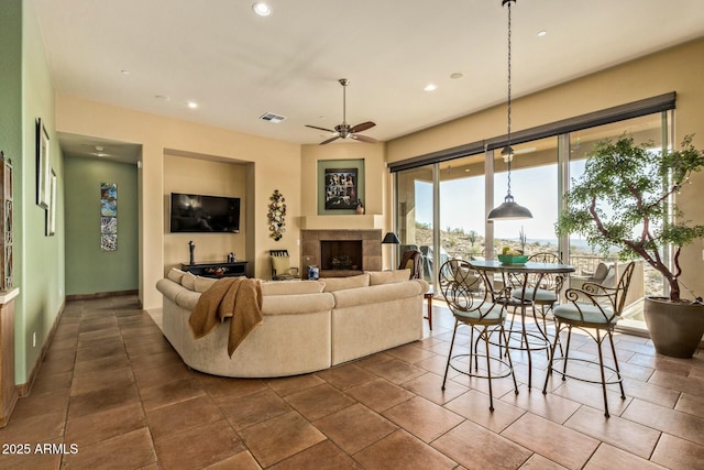 living room with ceiling fan and a tile fireplace