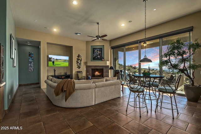 living room featuring a tiled fireplace, dark tile patterned floors, and ceiling fan