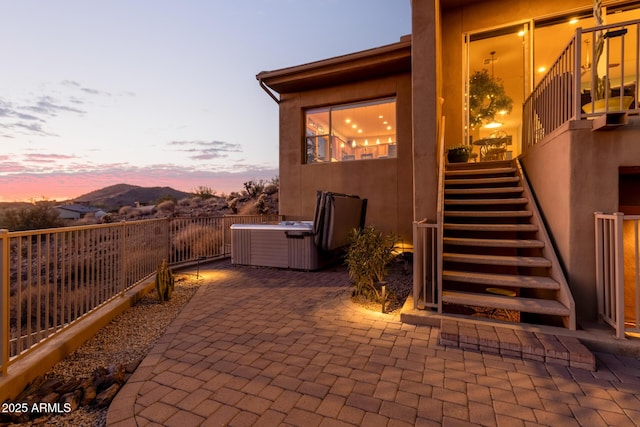 patio terrace at dusk featuring a hot tub