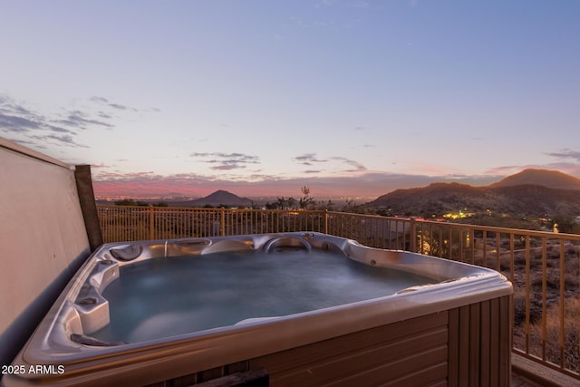 patio terrace at dusk featuring a hot tub and a mountain view