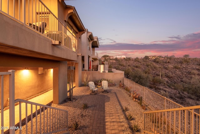 yard at dusk featuring a balcony and a patio area