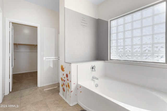 bathroom featuring a healthy amount of sunlight, a bathing tub, and tile patterned floors