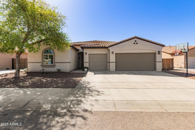 mediterranean / spanish home featuring fence, an attached garage, stucco siding, concrete driveway, and a tile roof