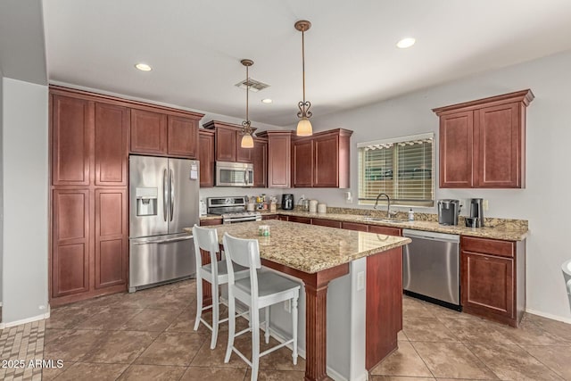 kitchen featuring visible vents, a sink, a center island, stainless steel appliances, and hanging light fixtures