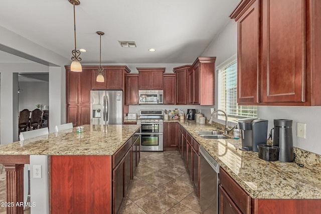 kitchen with visible vents, dark brown cabinets, a center island, appliances with stainless steel finishes, and a sink