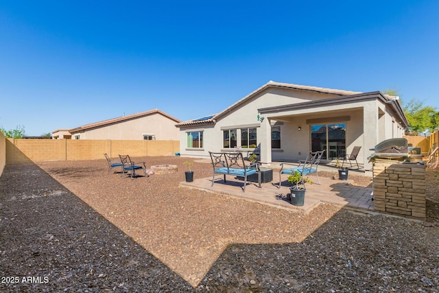 rear view of house with stucco siding, a fenced backyard, and a patio area